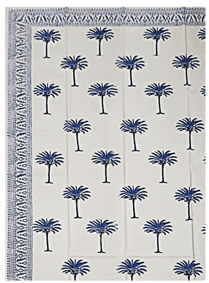 The Blue Palm Trees Tablecloth by Les Ottomans showcases a traditional blue palm tree block print and a decorative blue border on two edges.