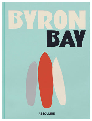 The book cover, titled "Byron Bay" from Assouline's Travel Series, showcases three surfboards in shades of gray, red, and white set against a teal background, beautifully encapsulating the spirit of Australia's renowned beach culture.