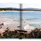 A glimpse into the Byron Bay book by Assouline unveils a lively beach scene, capturing surfers navigating the waves amidst lush greenery and clear skies, embodying the adventurous essence of our Travel Series.