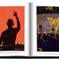 Open magazine displaying two photos of a dj performing at events with vivid lighting, featuring the Louis Vuitton: Virgil Abloh (Classic Cartoon Cover) by Assouline.