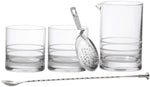 The Fortessa Crafthouse 5-Piece Mixing Set—three clear glass tumblers, a mixing pitcher, metal strainer, and twisted bar spoon—is arranged in a row on a white background.