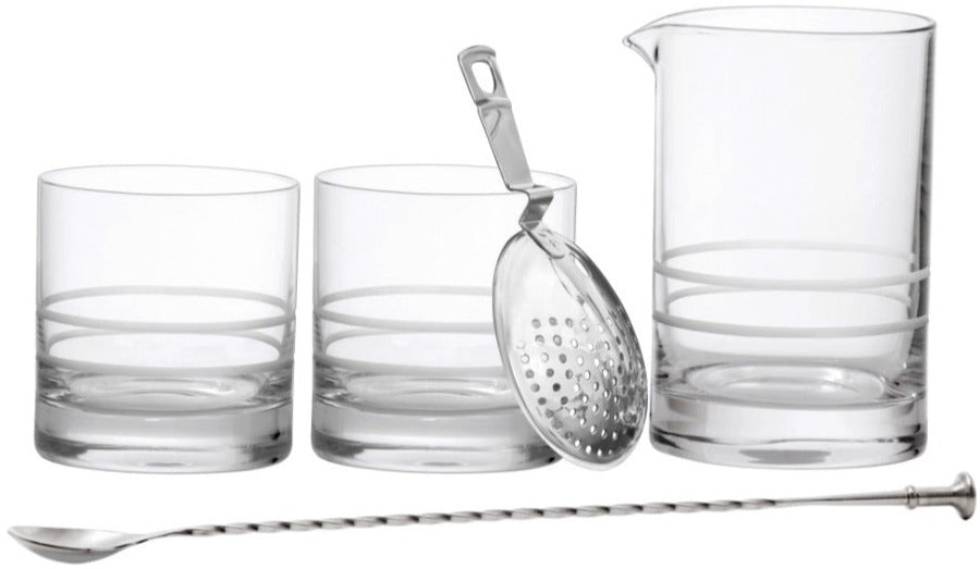 The Fortessa Crafthouse 5-Piece Mixing Set—three clear glass tumblers, a mixing pitcher, metal strainer, and twisted bar spoon—is arranged in a row on a white background.