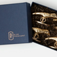 The Hailey Gold Place Card Holder Set by Blue Pheasant features 4 brass bird head holders in a gold finish, elegantly packaged in a dark blue Blue Pheasant box with crinkle paper.