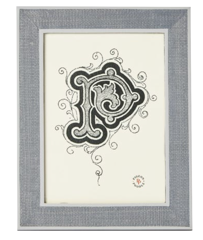 A framed artwork from Pigeon & Poodle’s Aberdeen Frame Collection features an ornate black and white letter "P" with decorative swirls on a white background and a small circular logo in the bottom right corner.
