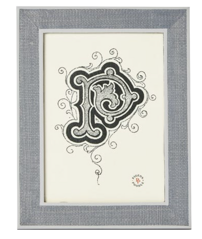 A framed artwork from Pigeon & Poodle’s Aberdeen Frame Collection features an ornate black and white letter "P" with decorative swirls on a white background and a small circular logo in the bottom right corner.