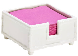 The Hampton Faux Bamboo Napkin Holder by Two's Company features a charming bamboo design and securely holds pink napkins, adding elegance to any table setting.
