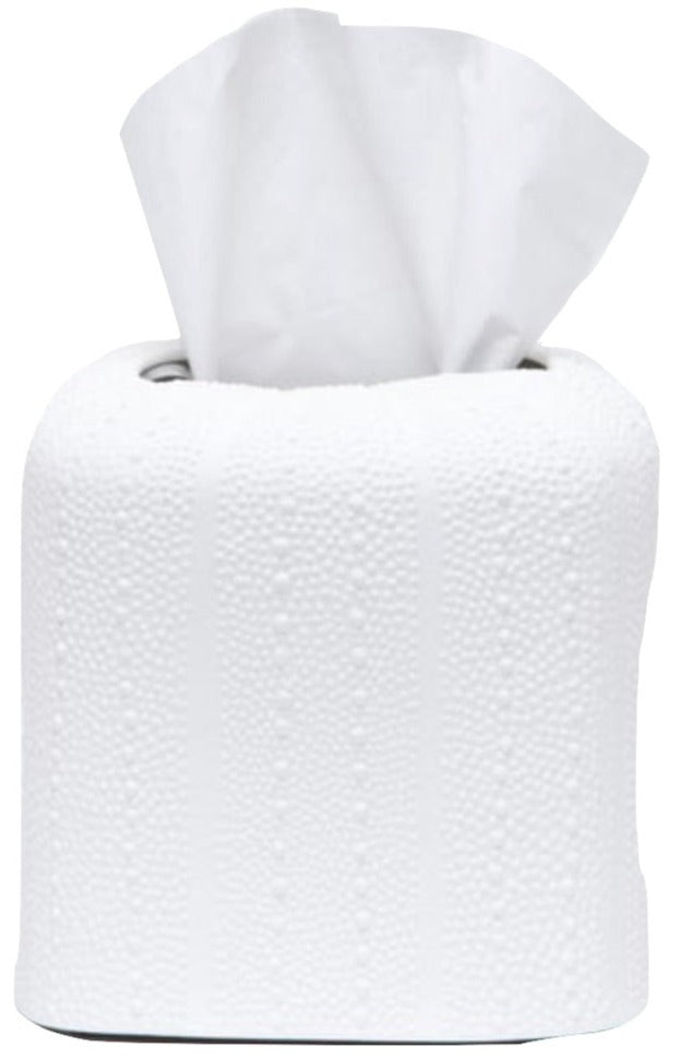A roll of white toilet paper from the Hilo Bath Collection by Pigeon & Poodle, with a tissue pulled halfway out from the center, rests on a porcelain surface.