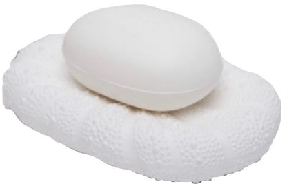 A white soap sits on the Hilo Bath Collection’s textured oval porcelain dish by Pigeon & Poodle, both in shades of white with a subtle sea urchin motif, against a plain background.