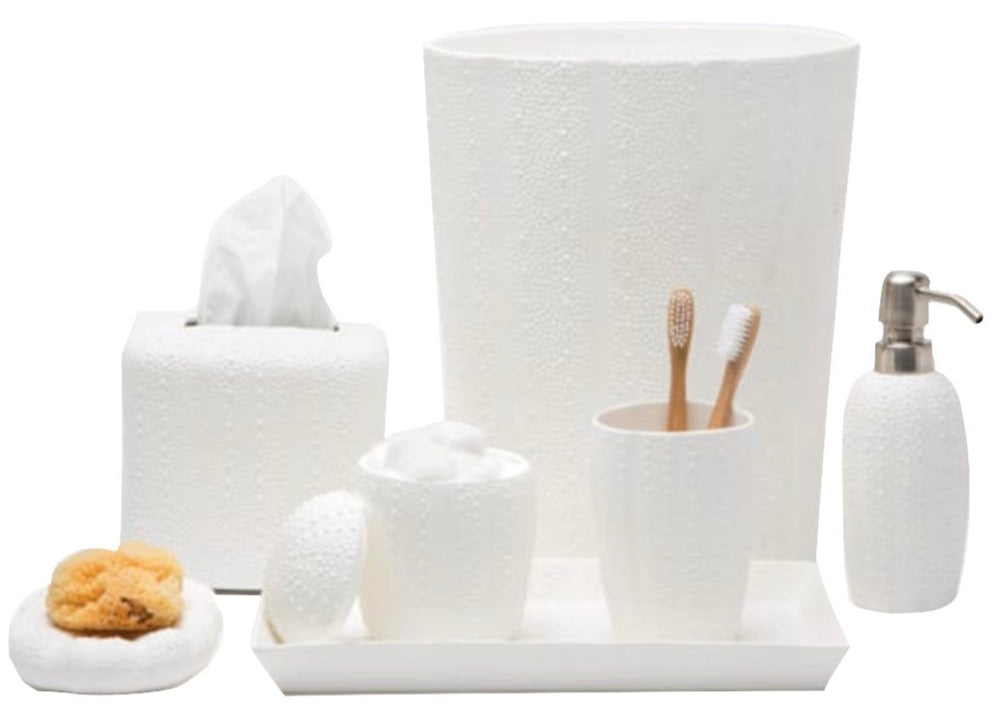 The Pigeon & Poodle Hilo Bath Collection includes a white porcelain set with a subtle sea urchin pattern: trash bin, tissue box, soap dispenser, toothbrush holder (with two brushes), two cups, tray, and bath sponges.