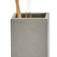 A wooden toothbrush and clear plastic stand rest in the Dannes Bath Collection’s gray, square holder by Pigeon & Poodle, exuding a sleek monochrome style—a true bath triple threat.
