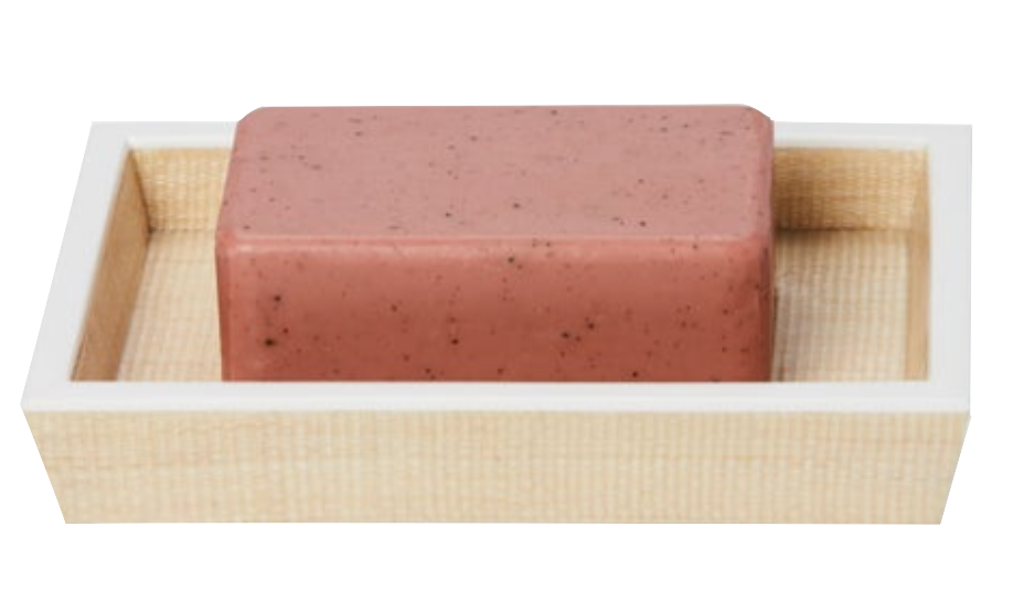A pink soap bar with dark specks rests in a light painted wood soap dish from the Maranello Bath Collection by Pigeon & Poodle.