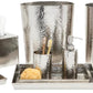 The Verum Bath Collection by Pigeon & Poodle features hand-hammered silver metal accessories, including a waste bin, tray, container, soap dispenser, toothbrush holder, tissue box cover, and cotton jar.