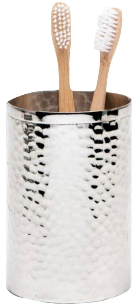 A silver, hand-hammered metal cup from the Pigeon & Poodle Verum Bath Collection holds two bamboo toothbrushes with white bristles.