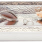 A rectangular hand-hammered metal tray from the Pigeon & Poodle Verum Bath Collection holds a pair of sunglasses, a coral piece, and two small white spheres.