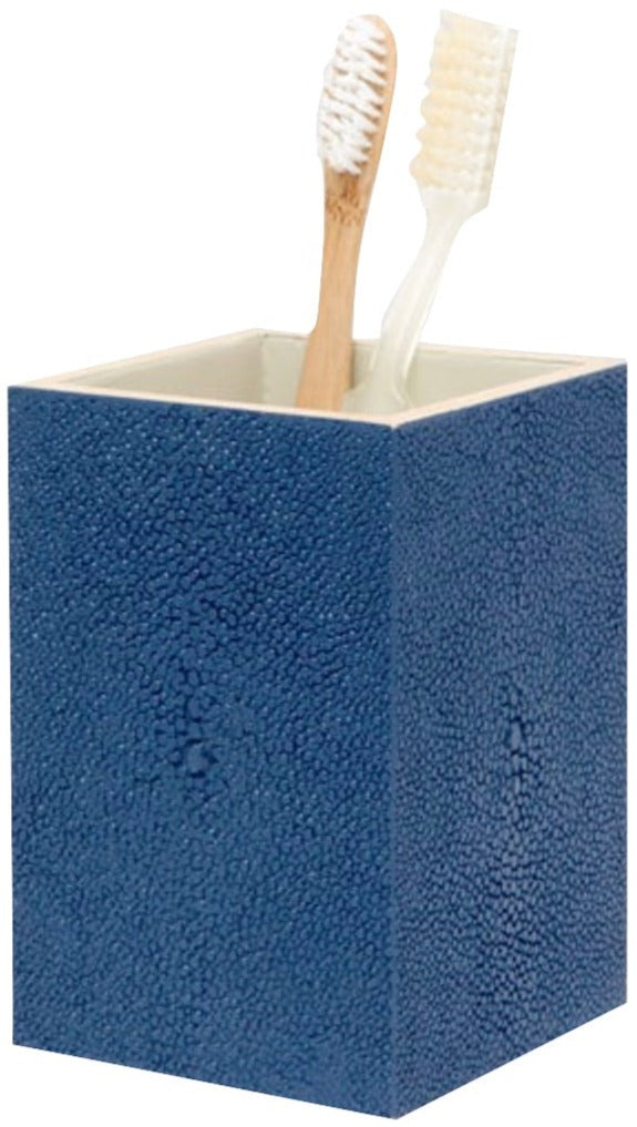 The Manchester Bath Collection by Pigeon & Poodle features a blue shagreen-textured toothbrush holder with two toothbrushes—one with a wooden handle and one with a clear handle.