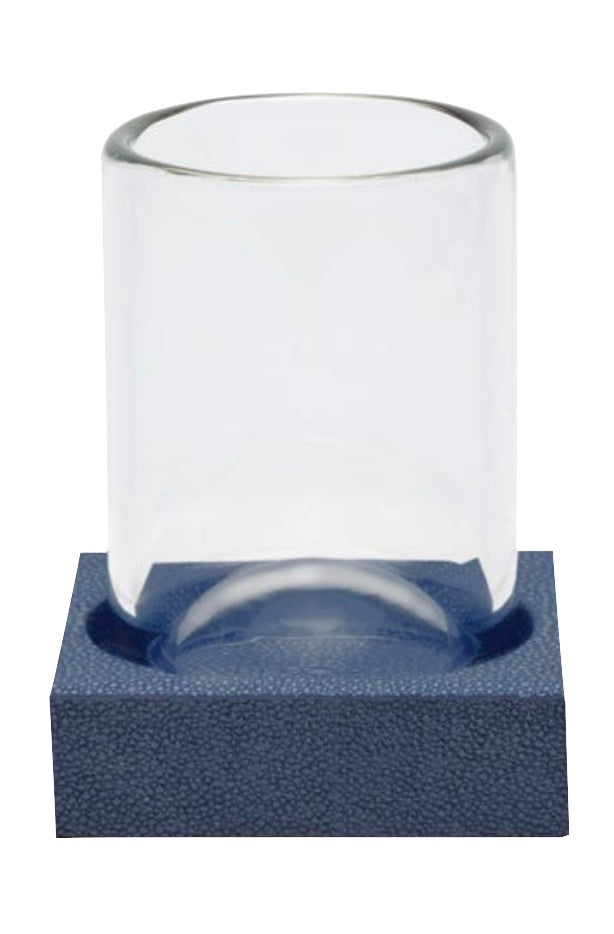 A clear glass dome from the Manchester Bath Collection by Pigeon & Poodle stands upright on a textured blue rectangular base featuring a subtle shagreen finish and circular indentation.