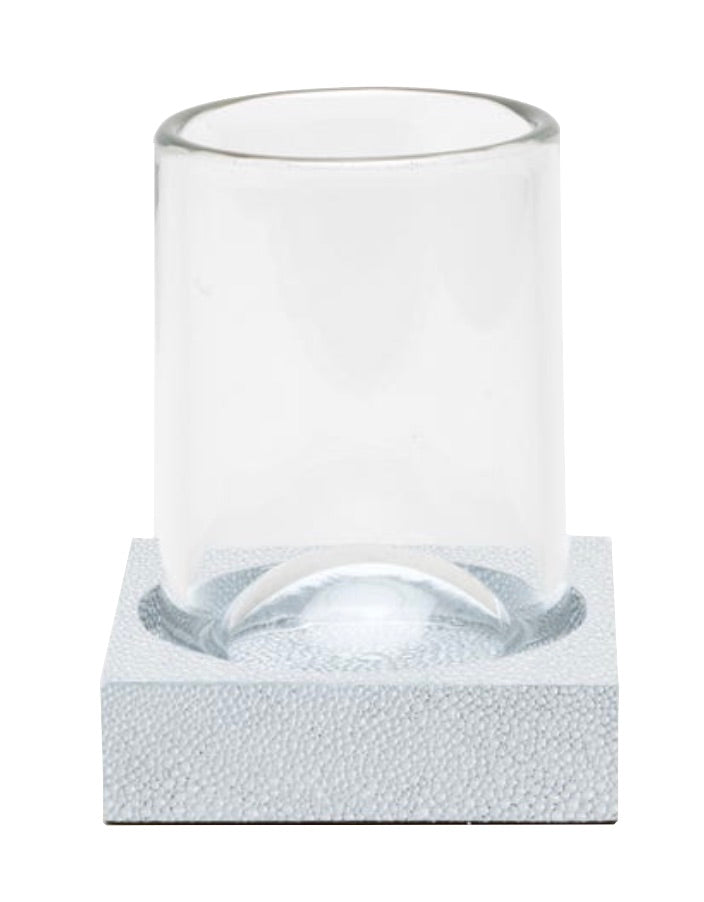 A clear glass sits upright on a textured, square, light-colored coaster from the Manchester Bath Collection by Pigeon & Poodle, set against a white background.