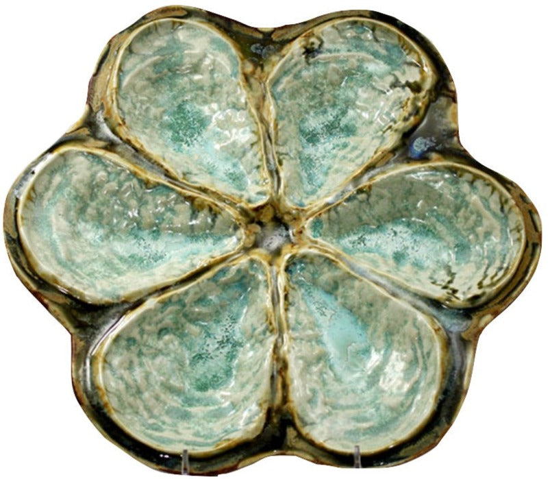The AE Ceramics Oyster Platter Collection features six shell-shaped compartments with a greenish-blue glazed finish, ideal for serving Oysters Rockefeller or oysters on the half shell.