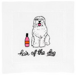 A white dog with long fur sits beside a pink bottle, resting on an elegant cotton napkin by August Morgan. Below, text reads "Hair Of The Dog Cocktail Napkins.