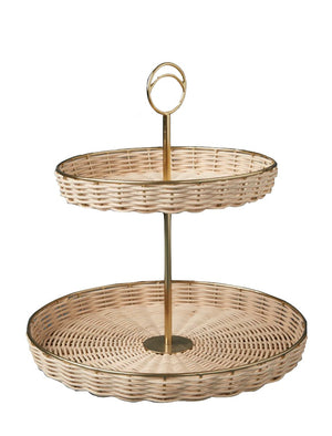 The Rowan Basket Collection by Be Home features a two-tier wicker serving tray with gold metal stand and handle, handcrafted in India from sustainable natural materials for eco-friendly elegance.