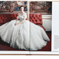 An open book titled "Little Book of Dior" by Graphic Image features a photograph of a woman in an elaborate white gown, capturing the essence of Parisian haute couture's new look silhouette. She is seated on a red velvet couch against an ornate backdrop, embodying the elegance synonymous with Christian Dior. Text and image credits are located on the lower right page.