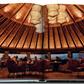 An open book from Assouline's "Hotel Wailea" reveals a restaurant with a round wooden ceiling, warm lighting, various seating arrangements, and an ocean sunset view. This Hawaiian-island escape evokes the serene ambiance of Maui's Hotel Wailea boutique resort.