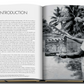 An open book featuring an image of a man holding a camera capturing iconic places, such as James Bond Destinations by Assouline.