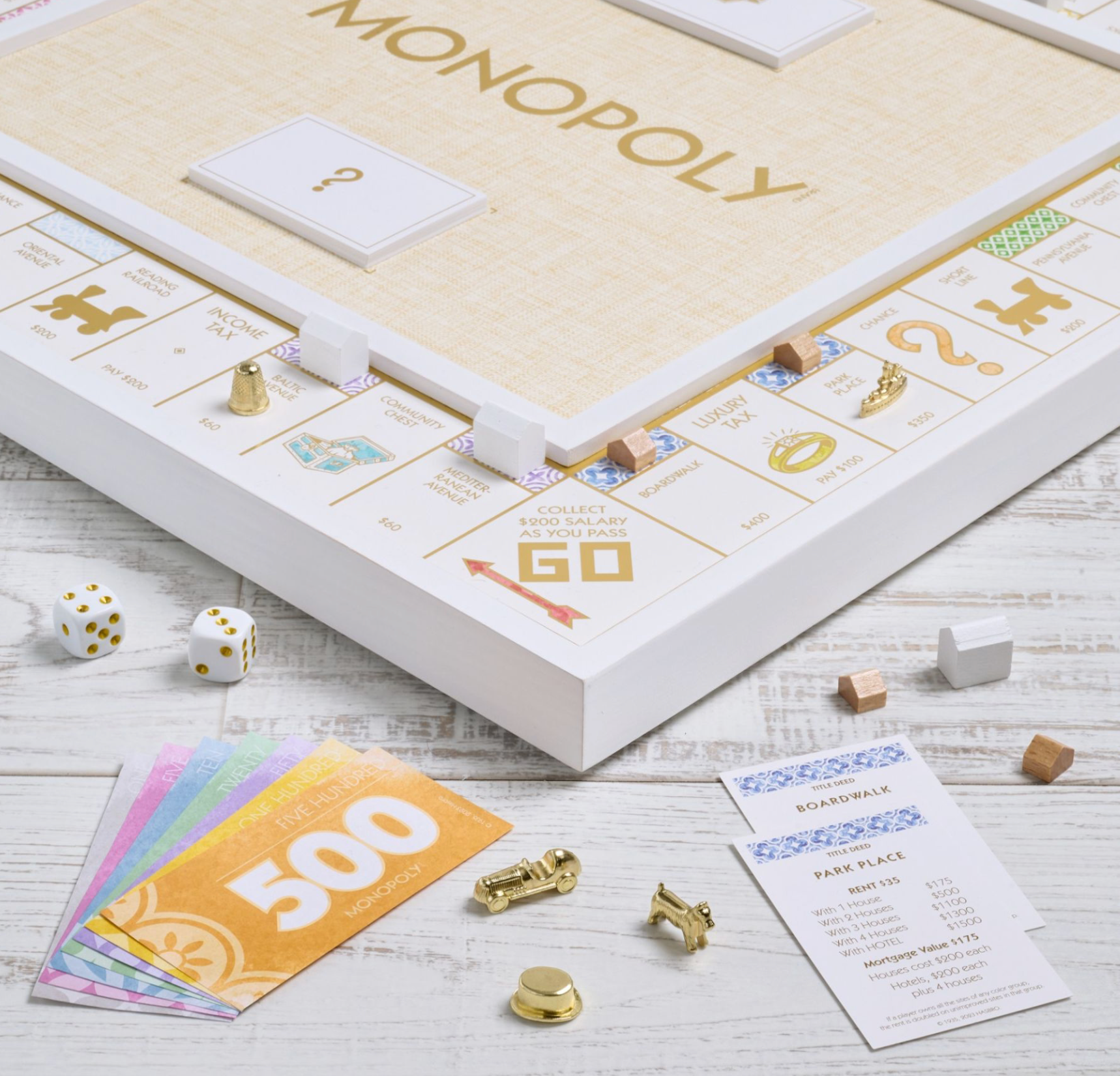Monopoly Bianco Edition setup with the premium game board, colorful money, dice, die-cast tokens, and property cards arranged on a white wooden surface. Welcome to the WS Game Company Monopoly Bianco Edition!