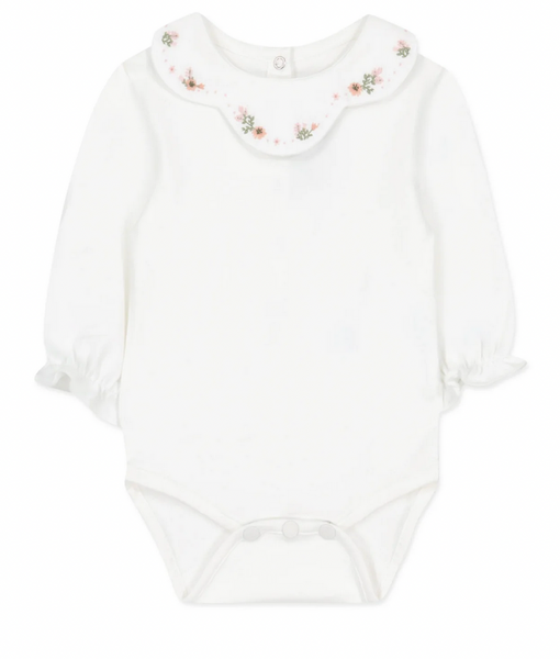 A long-sleeved white baby onesie with an embroidered flower collar and snap buttons at the bottom from Tartine et Chocolat.