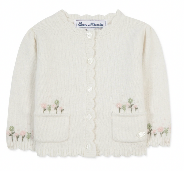 The Tartine et Chocolat Scallop Floral Embroidered Cardigan, by Tartine et Chocolat, is a soft and comfortable cream-colored baby cardigan featuring delicate Embroidery Fleurie on the pockets and scalloped edges. It also has a button-up front.