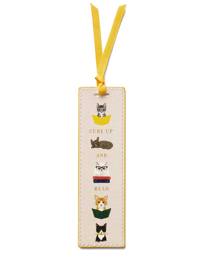 The Rifle Paper Co. Bookmark Collection features a whimsical rectangular illustrated bookmark with charming cats, books, the phrase "Curl up and read" in the center, and a yellow grosgrain ribbon.