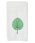 The Weezie x Meg Braff Fan Powder Bath Towel by Weezie Towels features a white design with an embroidered green leaf and a central handle, inspired by Meg Braff’s iconic Palm Beach style.