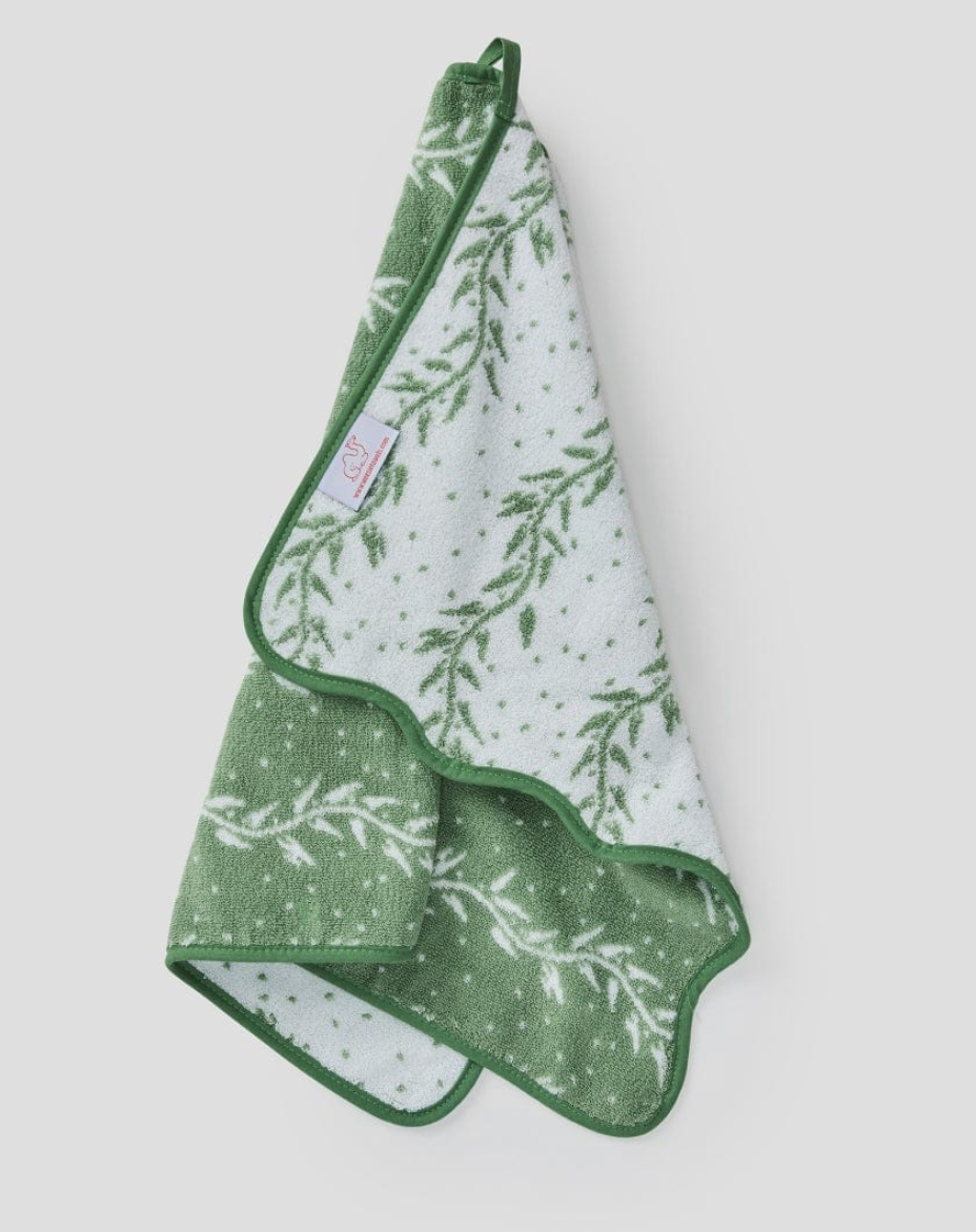 The Willow Scallop Towel Collection by Weezie Towels features a green and white leafy patterned bath towel with subtle scallop edging and a small fabric tag, perfect for adding a spa-like feel to your bathroom.
