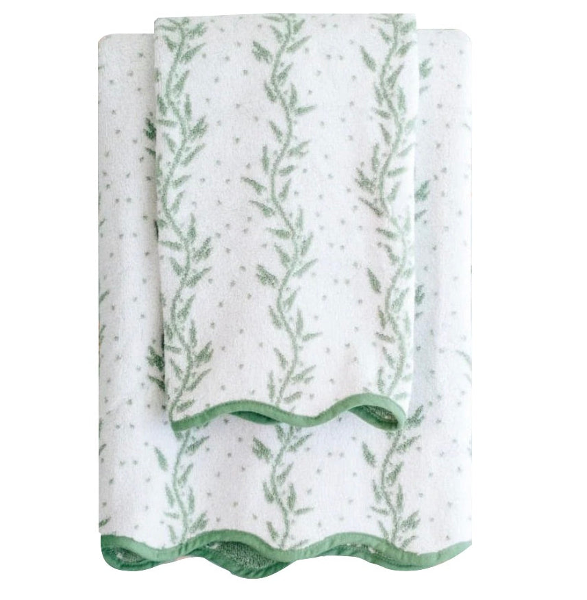 From the Willow Scallop Towel Collection by Weezie Towels, a smaller spa towel is folded atop a larger bath towel; both are white with green leafy vine patterns and scalloped edges.