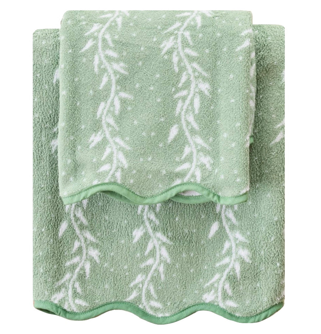 Two green bath towels from the Willow Scallop Towel Collection by Weezie Towels, featuring a white leaf and dot pattern with scalloped edges, are stacked for a spa-like touch.