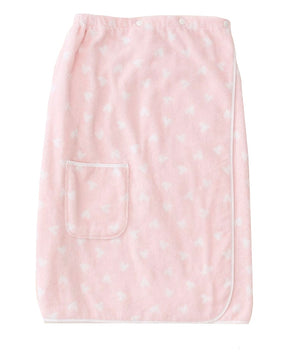 The Pink Hearts Towel Wrap by Weezie Towels features a light pink fabric with white heart patterns, a roomy pocket, white trim, and snap buttons along the top edge for a comfy, hands-free towel experience.
