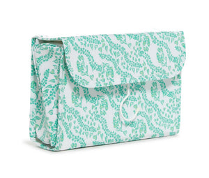 The TRVL Design Luxe Gloss Hanging Toiletry Case Collection features a rectangular case with flap closure, a green leafy print on white, and clear pockets for easy travel organization.