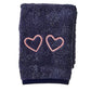 The Weezie Towels Makeup Towel is a folded navy terry towel embroidered with two pink heart outlines, offering a stylish and stain-resistant solution for your beauty routine.