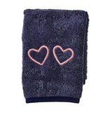 The Weezie Towels Makeup Towel is a folded navy terry towel embroidered with two pink heart outlines, offering a stylish and stain-resistant solution for your beauty routine.