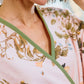 A person wearing the Vivian Cherry Blossom Robe by Weezie Towels, a soft pink floral velour robe with green trim and bell sleeves, photographed from the neck down.