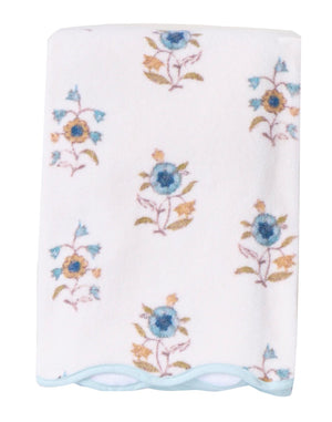 A folded white HIVE Home, Gift and Garden Floral Scallop Cora towel features blue and yellow floral patterns with a light blue scalloped trim along the edge.