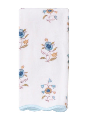 The HIVE Home, Gift and Garden Floral Scallop Cora Towel Collection features a folded white bath towel adorned with blue and yellow flowers for an elegant touch of luxury.