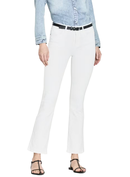 A person wearing a light blue denim shirt paired with the Frame Le Crop Mini Boot white flared pants by Frame, accessorized with a black belt and black sandals, standing against a plain white background.