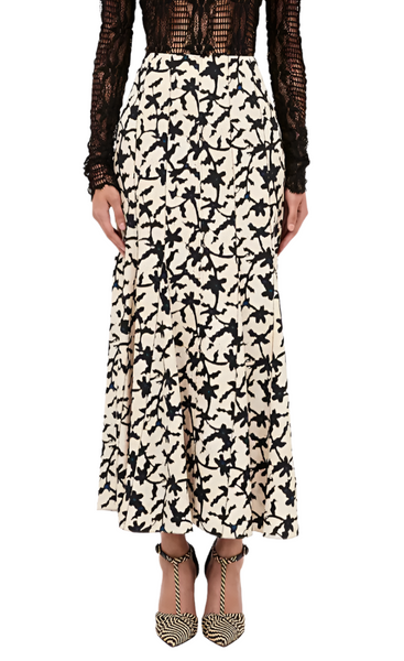 A person wearing a black lace top and the Ulla Johnson Kellia Skirt, an ankle-length white skirt with a vintage batik print from Ulla Johnson, paired with black and white patterned high heels.