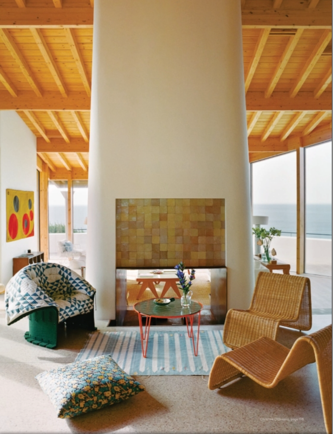 Experience true interior design authority for unique homes with inspiration from AD At Home: Architectural Digest by Penguin Random House, featuring modern living spaces with tall white fireplaces, wicker chairs, round tables, patterned pillows, and breathtaking ocean views through expansive windows.