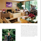 A modern living room, as featured in “AD At Home: Architectural Digest” by Penguin Random House, showcases true interior design flair with wood-paneled walls, contemporary furniture, sculptures, plants, and artwork. Radiating style, this unique home is brought to life as a man in a black jacket smiles at the camera by the entrance.