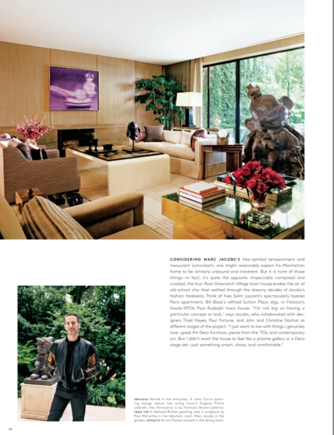 A modern living room, as featured in “AD At Home: Architectural Digest” by Penguin Random House, showcases true interior design flair with wood-paneled walls, contemporary furniture, sculptures, plants, and artwork. Radiating style, this unique home is brought to life as a man in a black jacket smiles at the camera by the entrance.