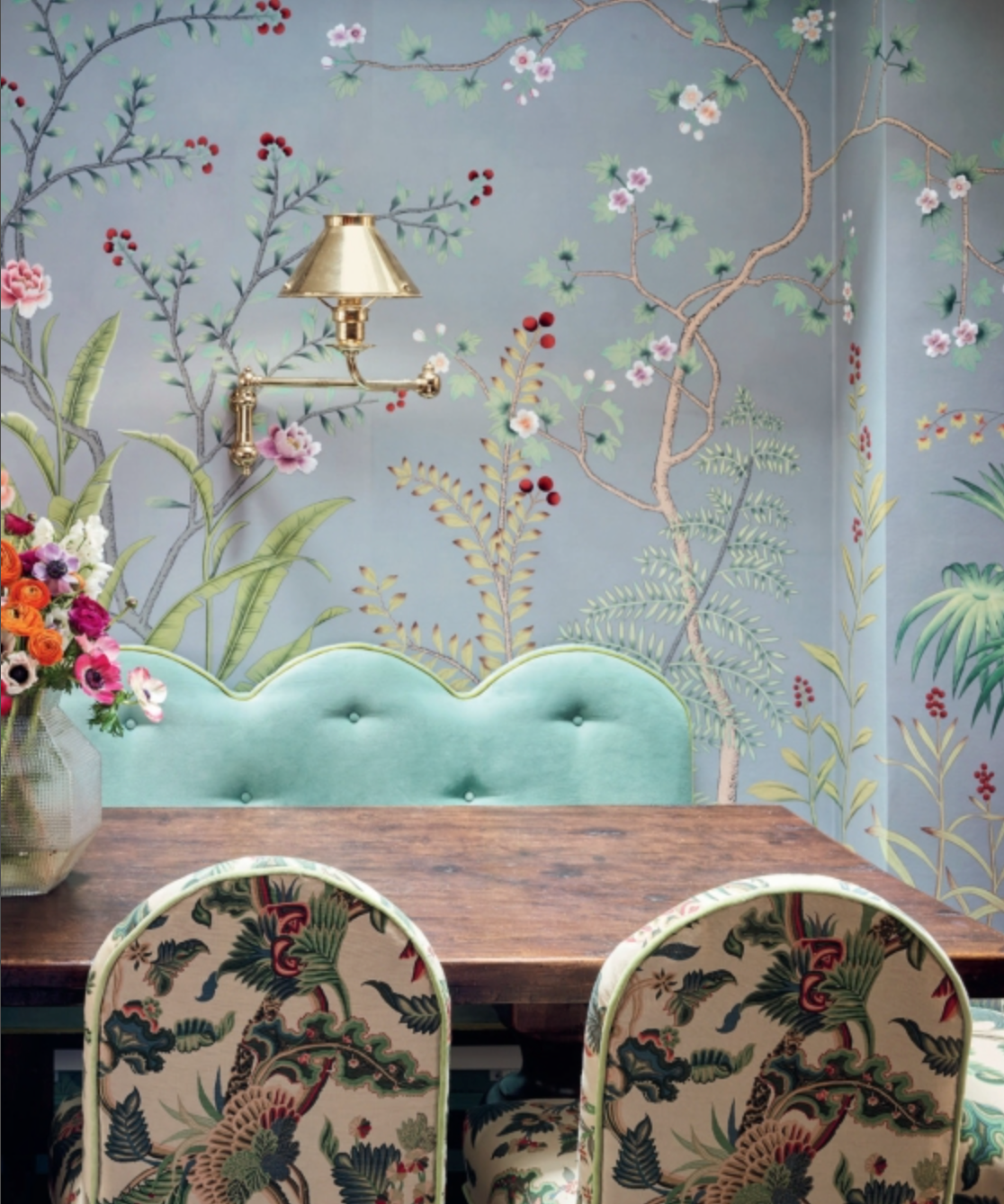 Dining table and patterned chairs in front of a scalloped mint green bench against a wall covered in de Gournay: Hand-Painted Interiors wallpaper.