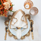 A formal table is set with a Kim Seybert Daisy Placemat, plate, napkin with ring, bamboo-handled fork and knife, two glass goblets, and orange flowers—ideal for elegant outdoor gatherings.