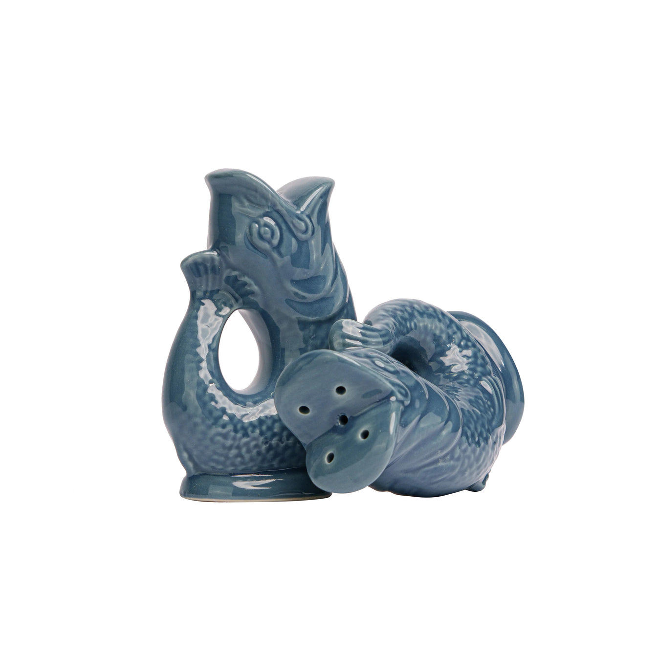 The Original Gluggle Jug Fish Salt & Pepper Shakers feature two blue ceramic, fish-shaped shakers—one upright and one lying down—with holes on the bottom, inspired by the classic Gluggle Jug design.